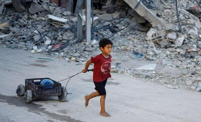 A child pulling a loaded cart through destruction
