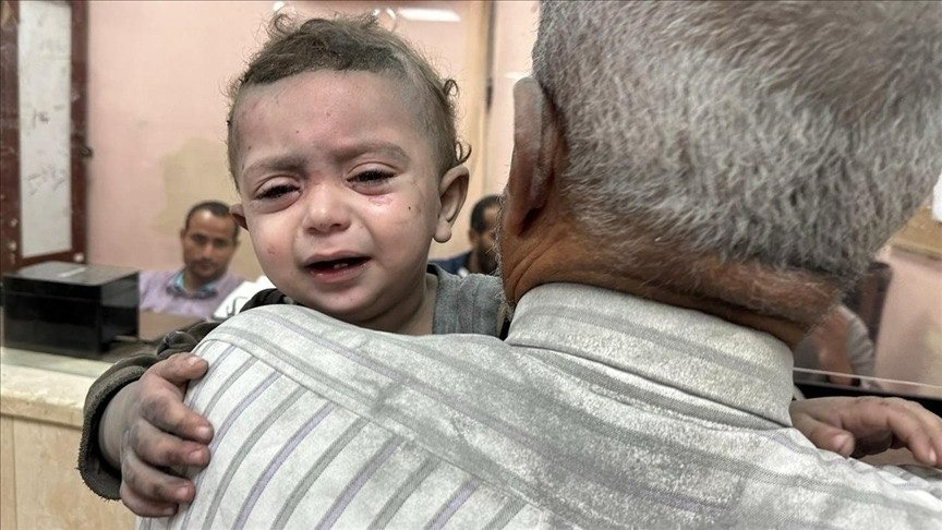 A child crying in the arms of an older man amidst the destruction